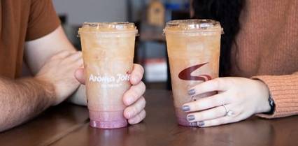 Two people holding cold beverages from Aroma Joe’s